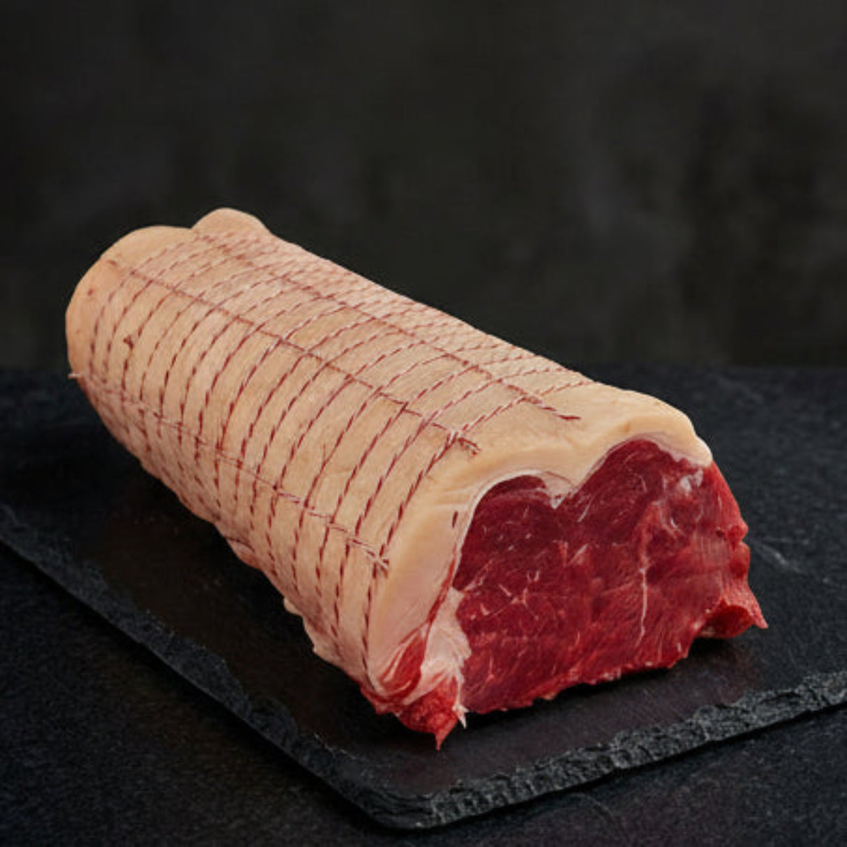 Rolled raw meat on a dark surface