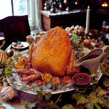 Roasted turkey crown on a decorative platter with side dishes on a festive table.
